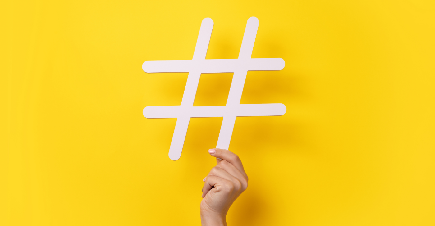 Yellow background and a hand holding up a # sign. This symbolizes web content.