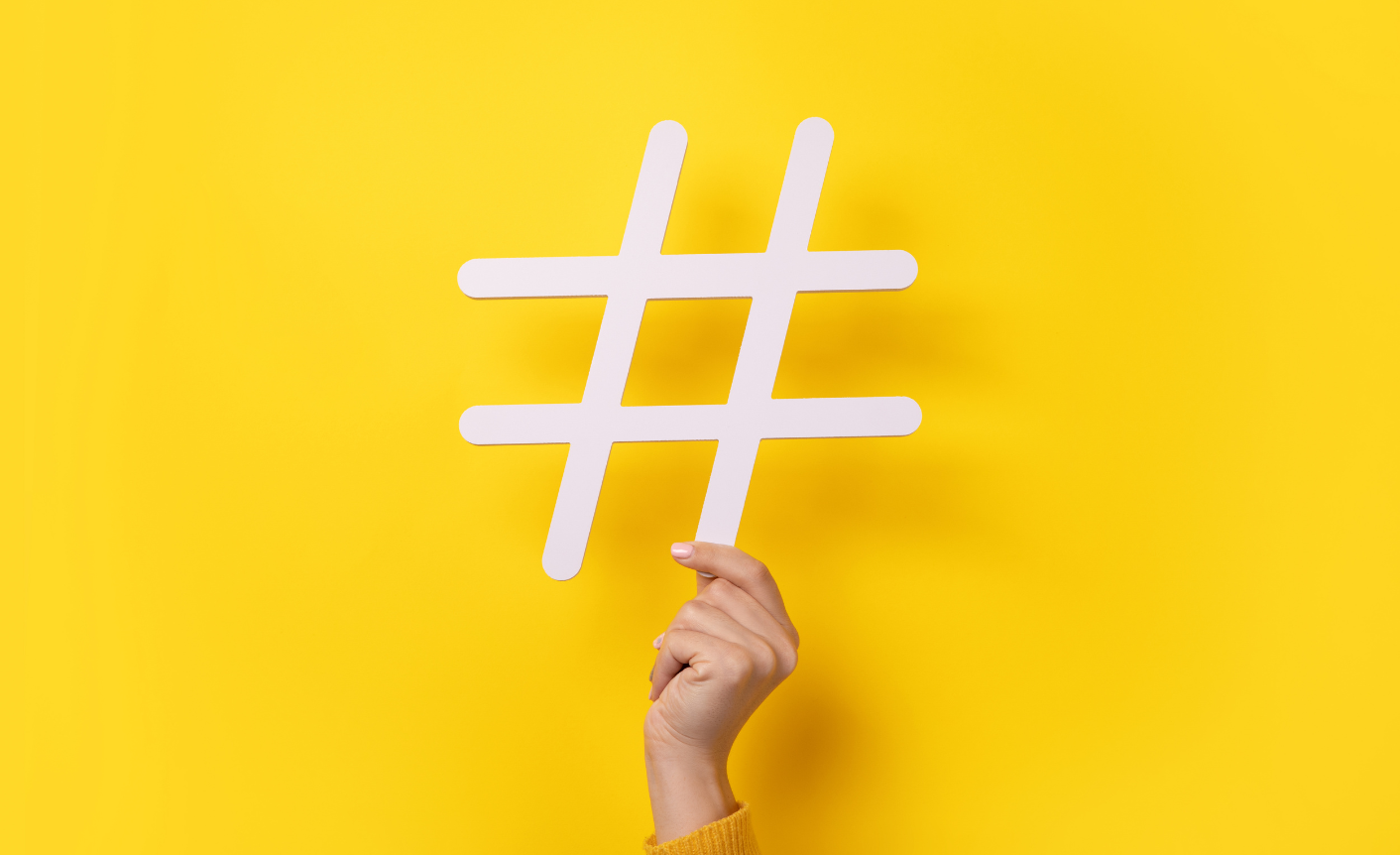 Yellow background and a hand holding up a # sign. This symbolizes web content.