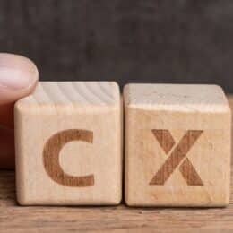 Wooden blocks with the letters C and X that symbolize customer experience content which uses clear language.