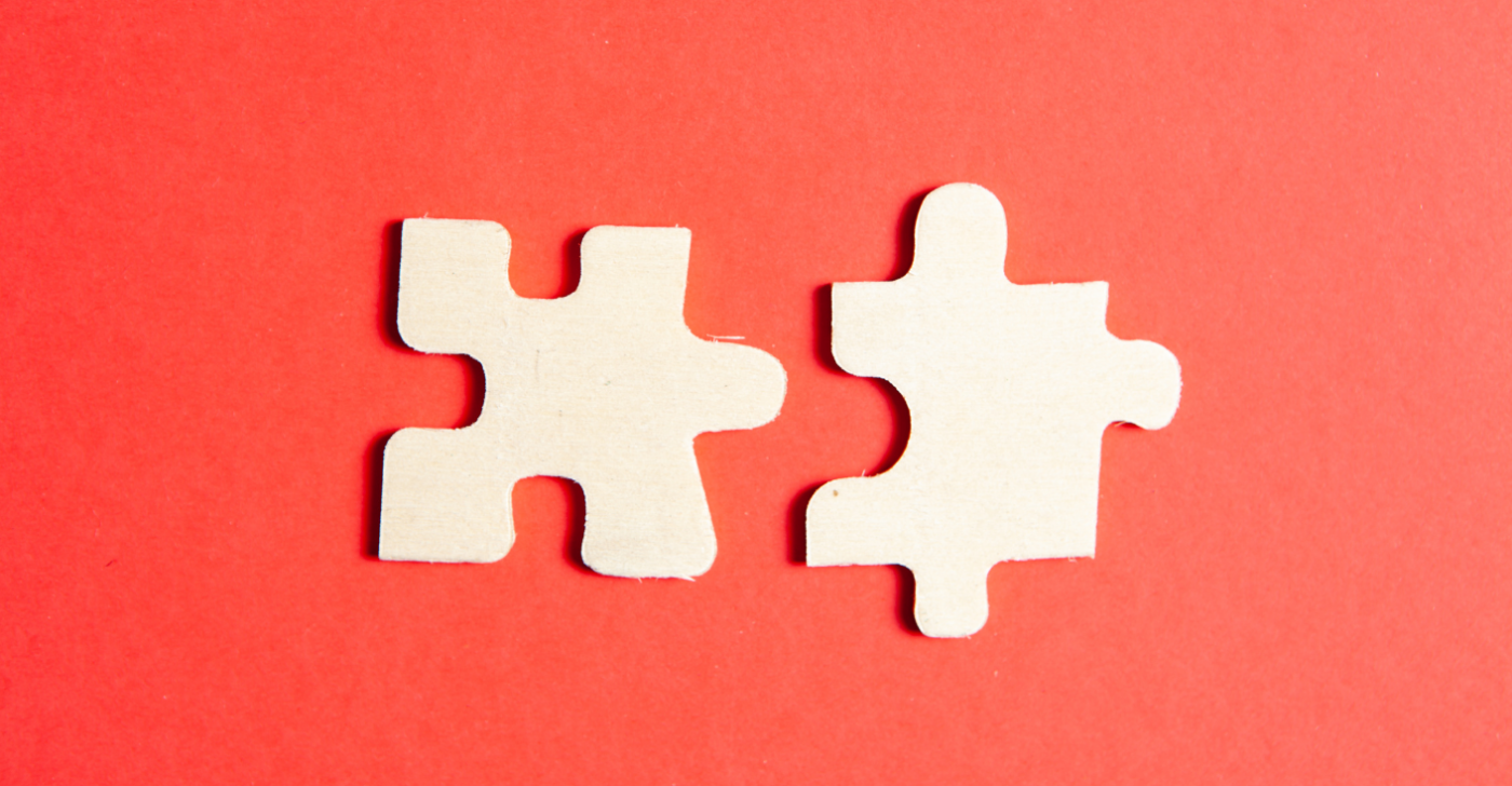 Two white puzzle pieces on a red background to symbolize the unification of two different content operations after a merger and acquisition.