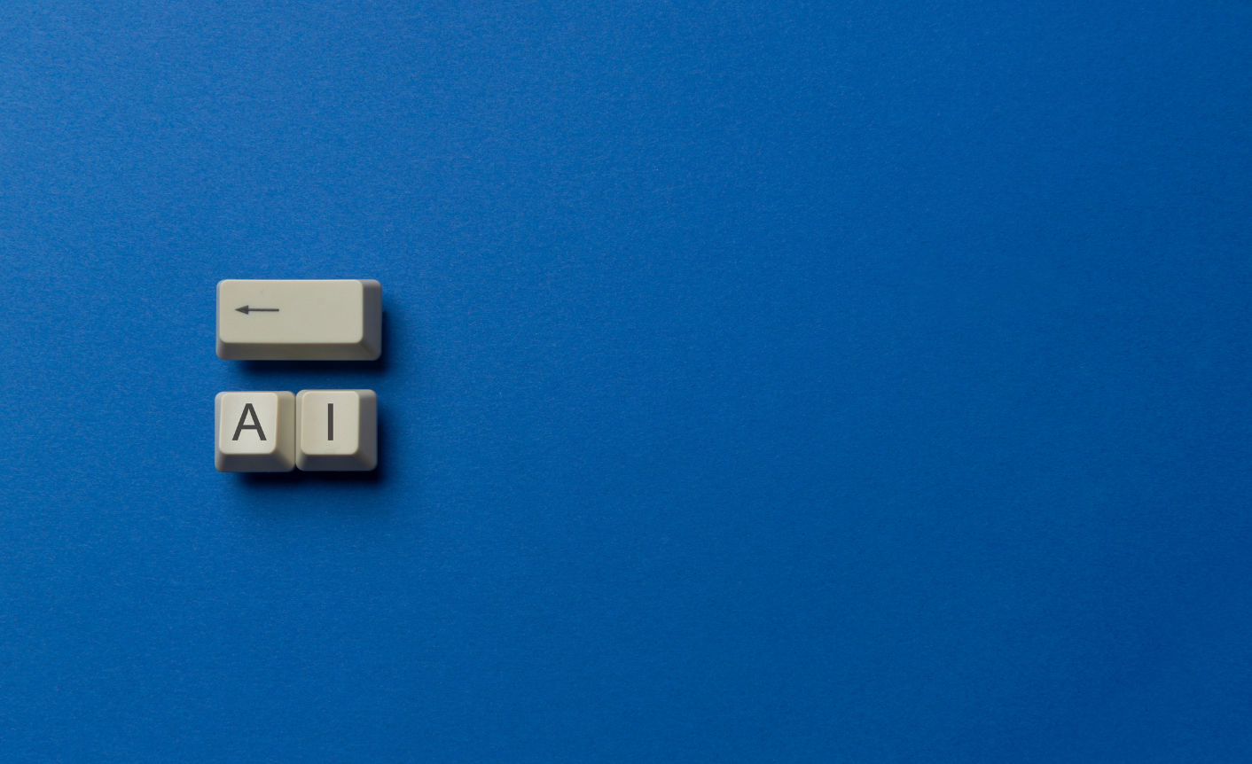 On a dark blue background are three old-fashioned keyboard keys. One with an arrow pointing backwards and the other two with the letters "A" and "I" on them.