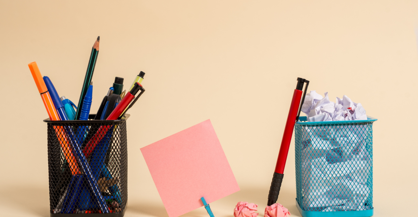 On a beige background, there are two wire baskets either side of a pink post-it note. The basket on the left is filled with pens and pencils and the basket on the right is filled with scrunched up paper. This is meant to symbolize that a lot of people create content at an enteprise.