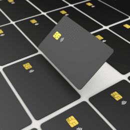 Numerous black credit cards with golden chips, one card angled and raised above the others.
