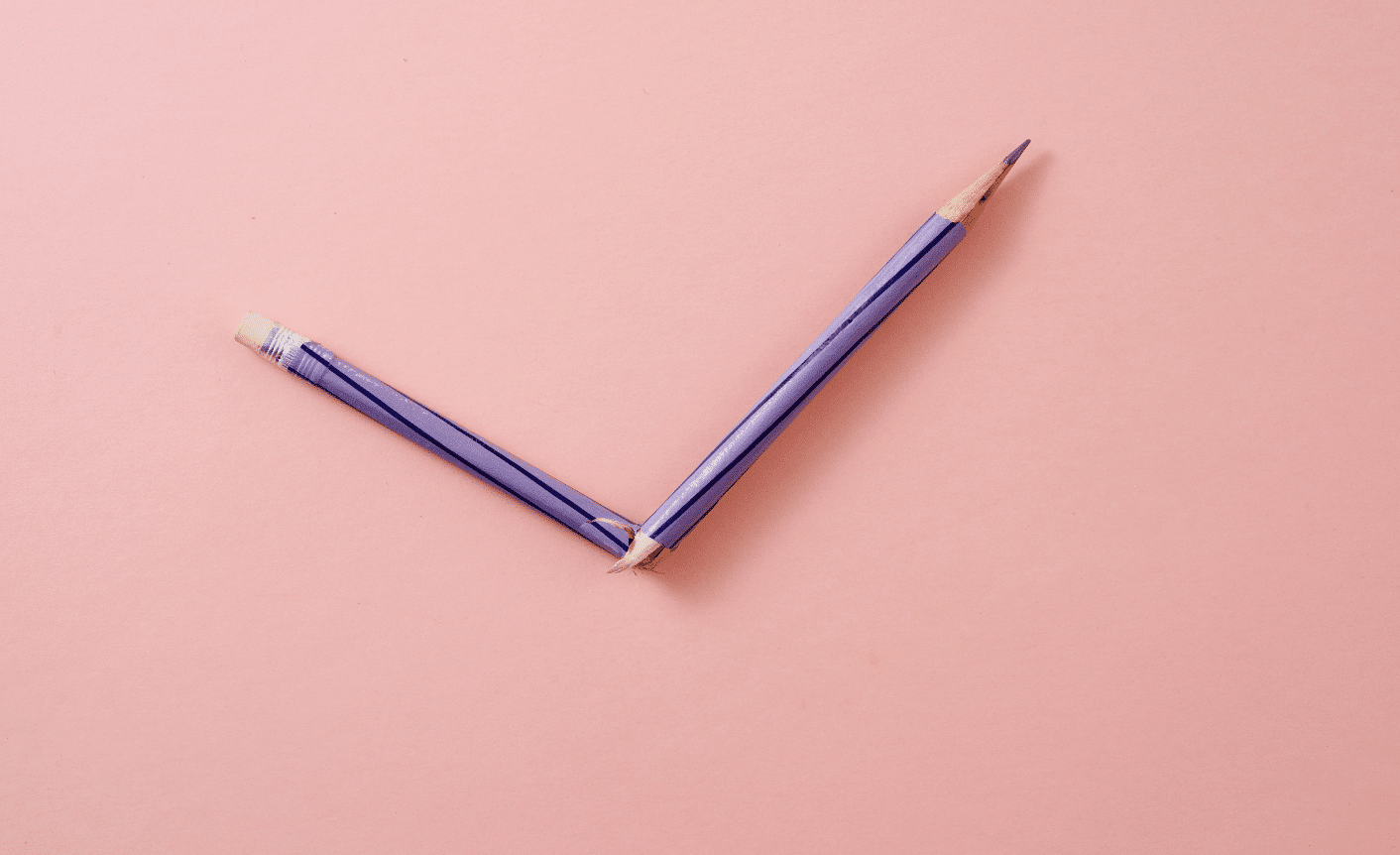 Writing-Mistakes-Blog-min A broken pencil on a pink background symbolizing content errors.