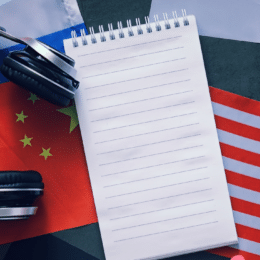 Seamless content localization starts with good source content. An image of a blank notebook and headphones and a pen on numerous countries flags.
