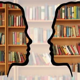 The silhouettes of two people talking to each other are depicted in front of a bookshelf; this symbolizes translation management with a translation management system.