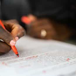 The hand of a person editing some copy symbolizes AI sentence rewriter tools.